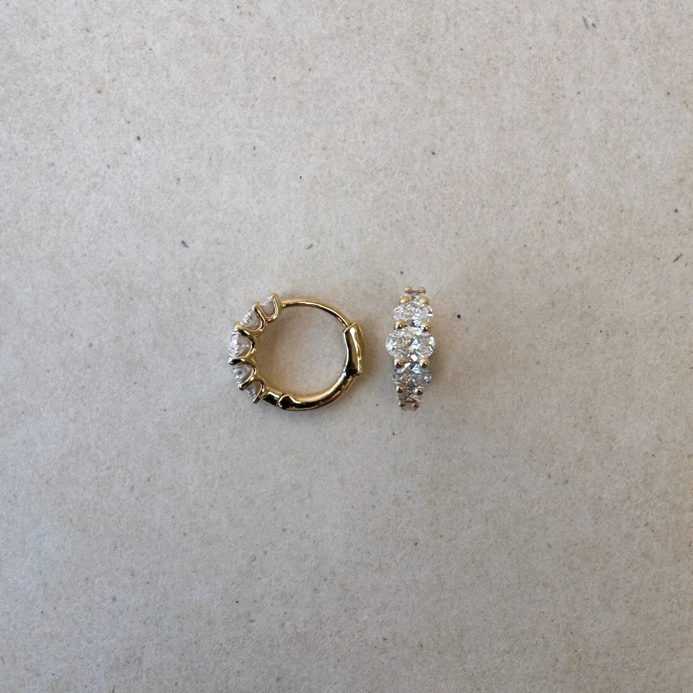 Lucerne Oval Huggies in 18ct gold shown side by side, highlighting symmetry and oval diamond layout