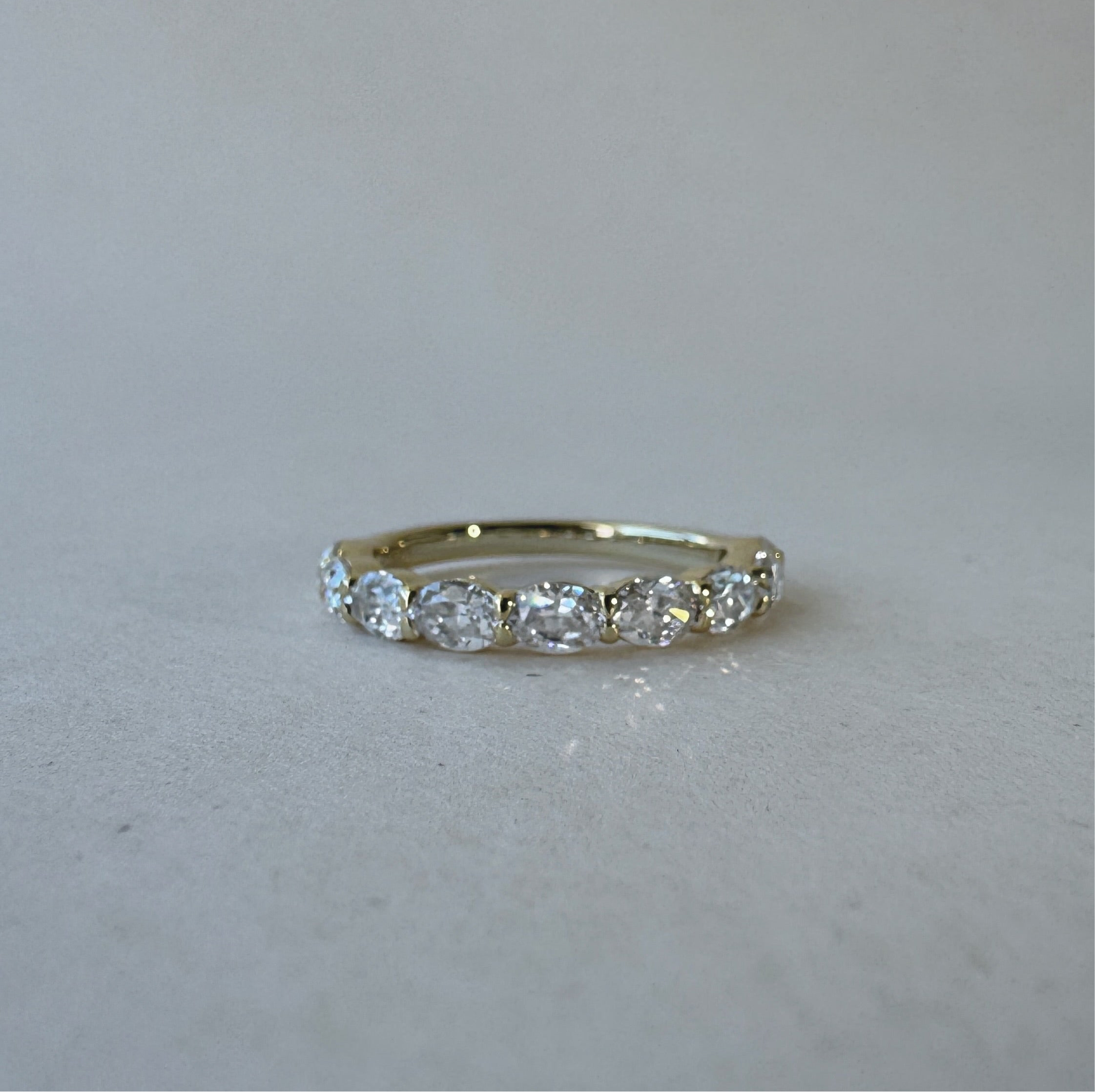 Gold ring with diamonds on a light gray background