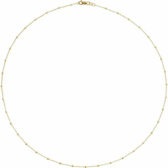 A gold beaded cable necklace with a clasp, laid out on a plain background.