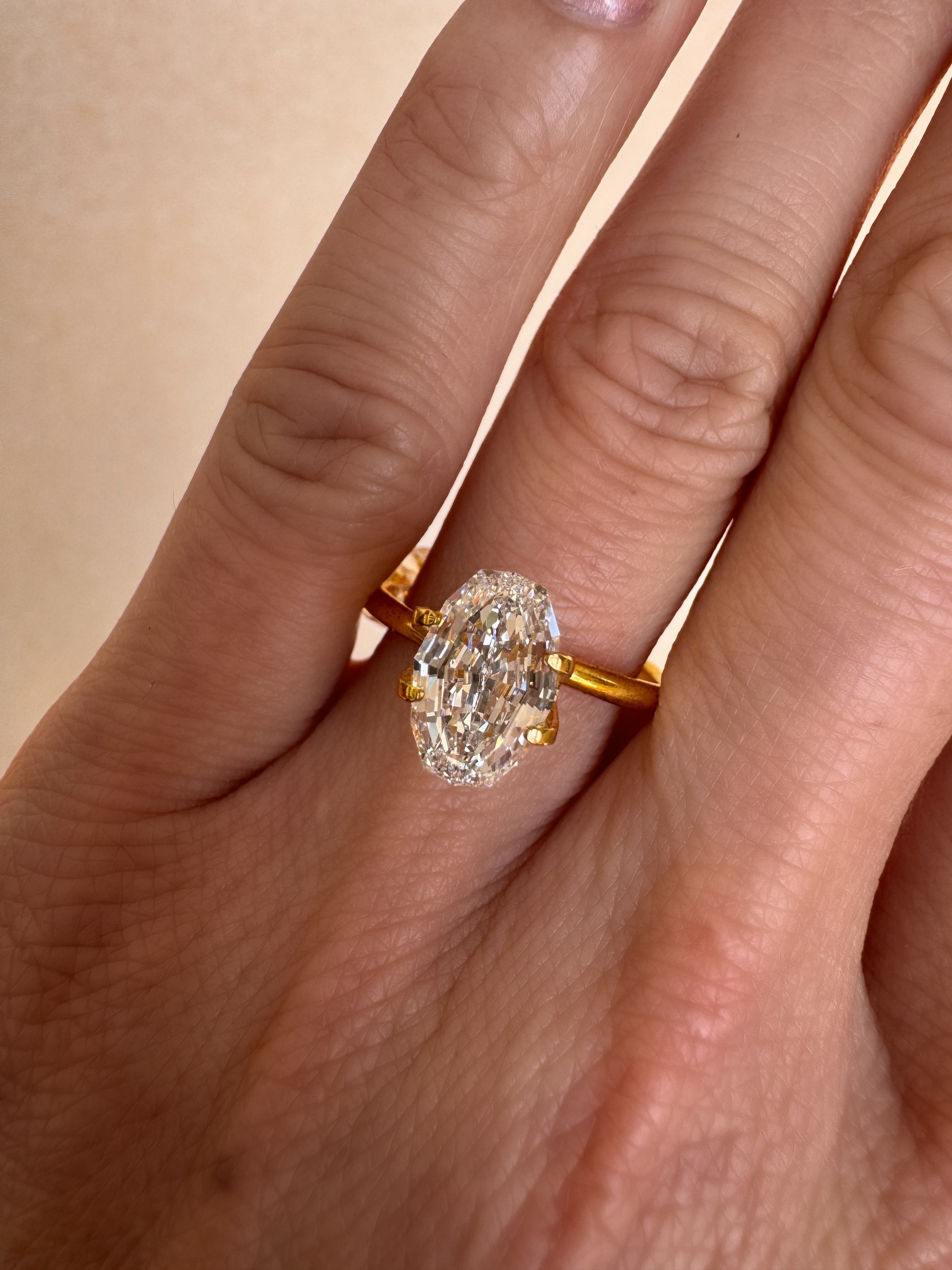 A hand modeling a yellow gold engagement ring set with a 2.09ct oval step cut lab-grown diamond. A bespoke custom ring design concept by MOHSTEN jewellery studio in Auckland, New Zealand