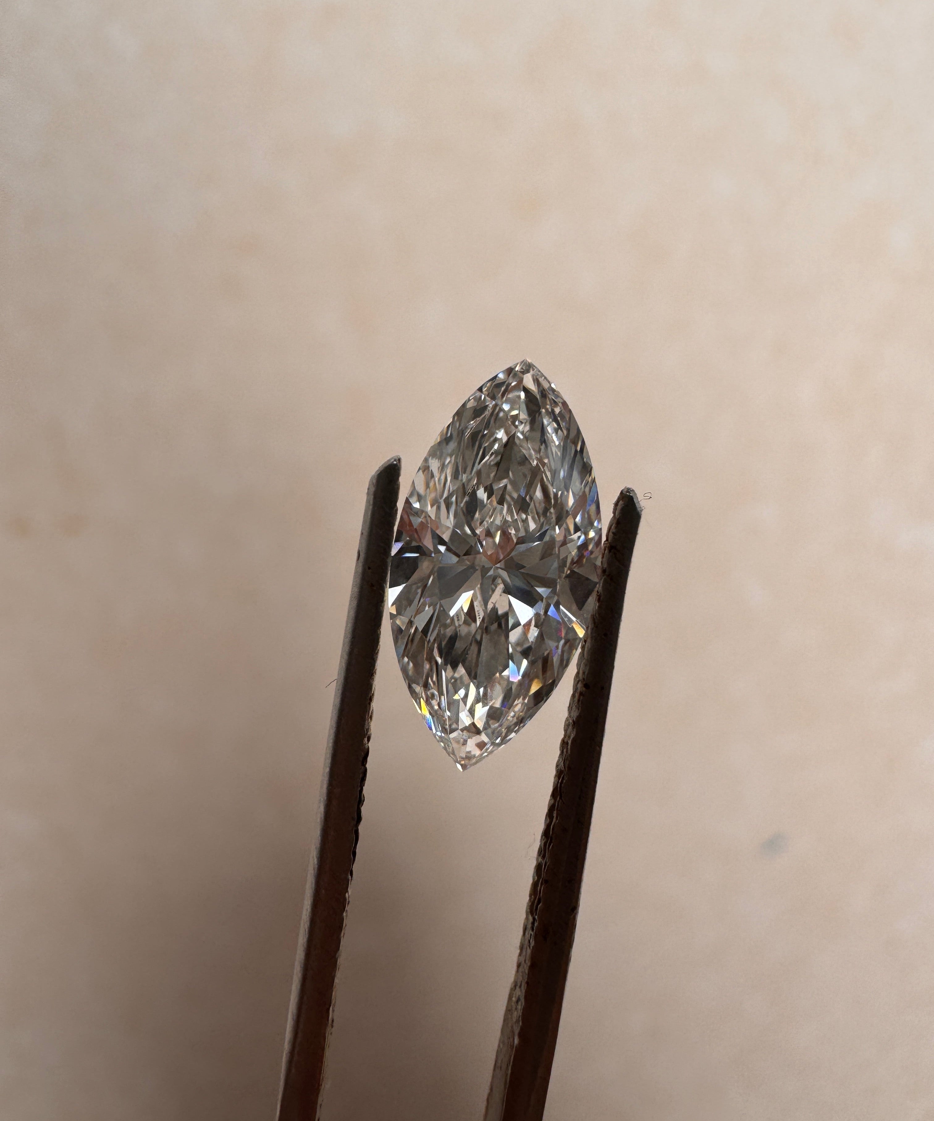 Close-up of a 2.01 carat marquise cut lab diamond held by tweezers, showcasing its brilliant E colour and VVS2 clarity. Available for custom architectural ring commissions at MOHSTEN in Auckland, NZ