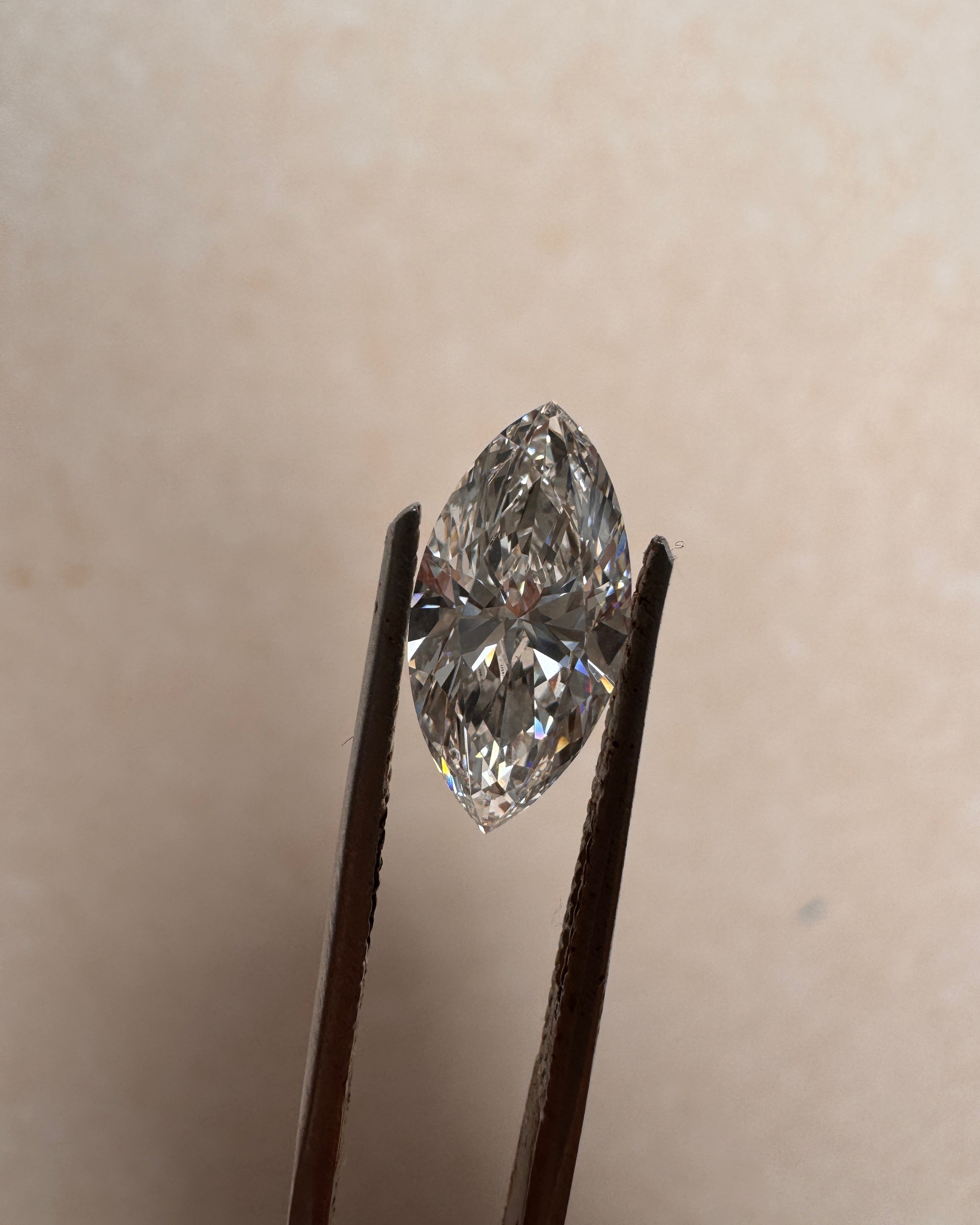 Close-up of a 2.01 carat marquise cut lab diamond held by tweezers, showcasing its brilliant E colour and VVS2 clarity. Available for custom architectural ring commissions at MOHSTEN in Auckland, NZ