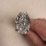Close-up of a 2.09ct oval step cut lab-grown diamond held in a prong tool, showcasing its striking linear facets and exceptional clarity. Sourced for MOHSTEN bespoke custom engagement rings in Auckland, New Zealand.