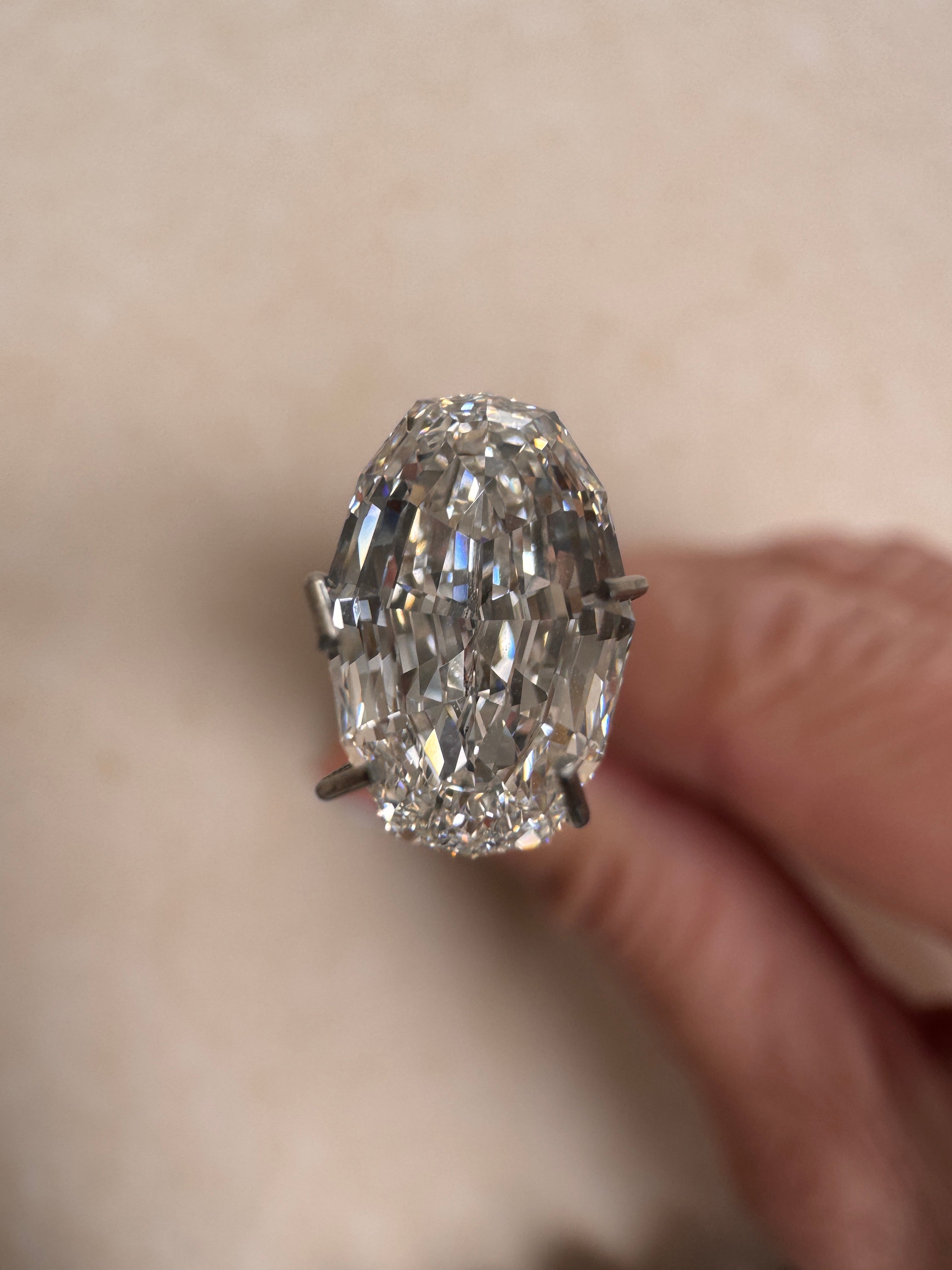 Close-up of a 2.09ct oval step cut lab-grown diamond held in a prong tool, showcasing its striking linear facets and exceptional clarity. Sourced for MOHSTEN bespoke custom engagement rings in Auckland, New Zealand.