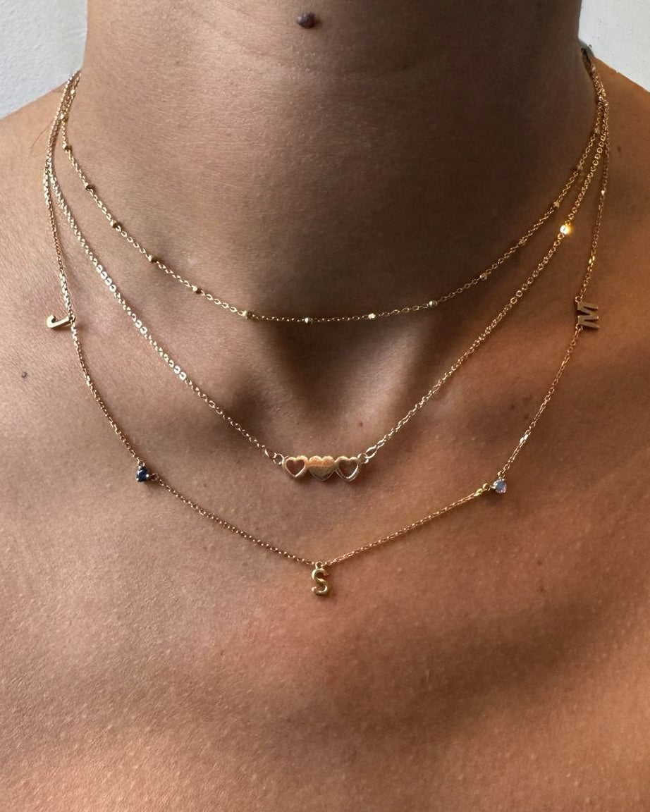 Close-up of a person wearing gold necklaces with a neutral background