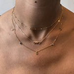 Close-up of a person wearing gold necklaces with a neutral background