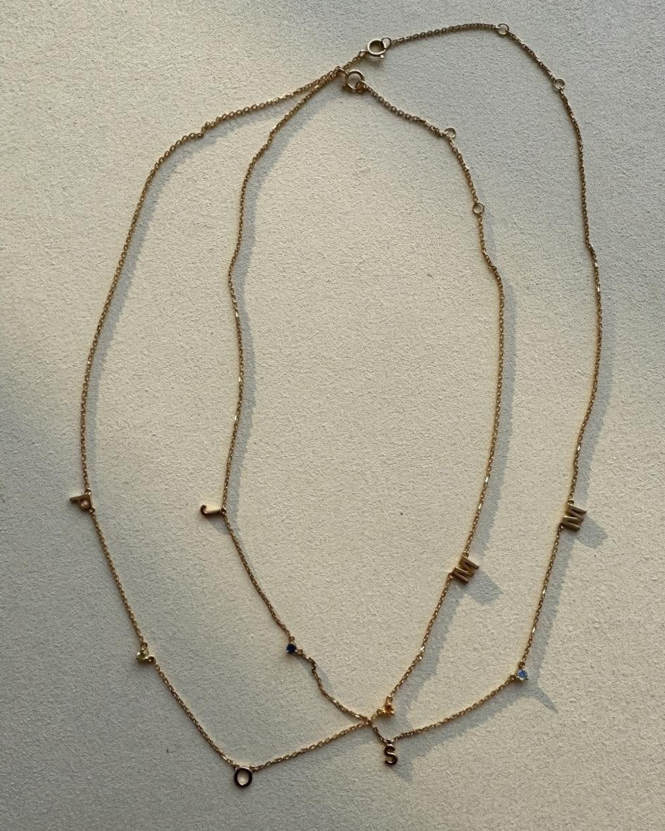 Two gold necklaces with small beads on a light gray background