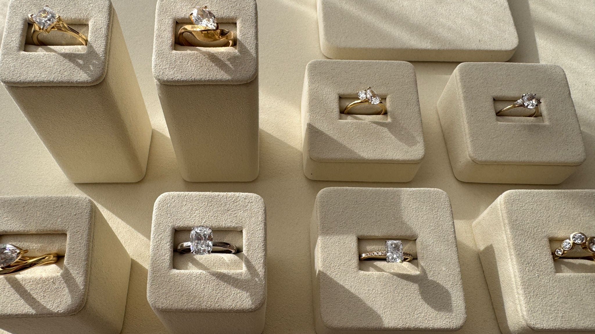Multiple diamond rings in small beige boxes on a matching surface