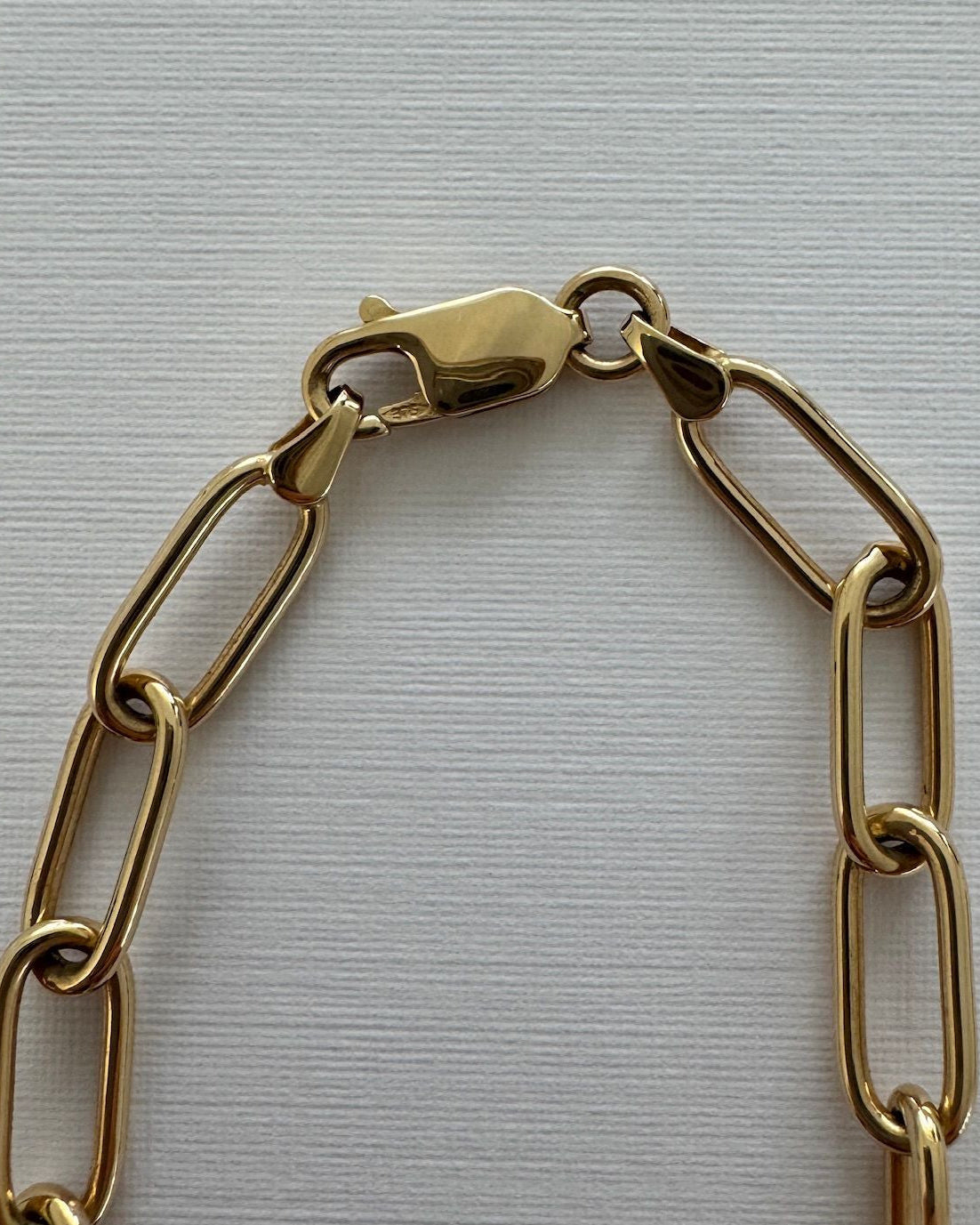 Gold chain bracelet on a light gray background