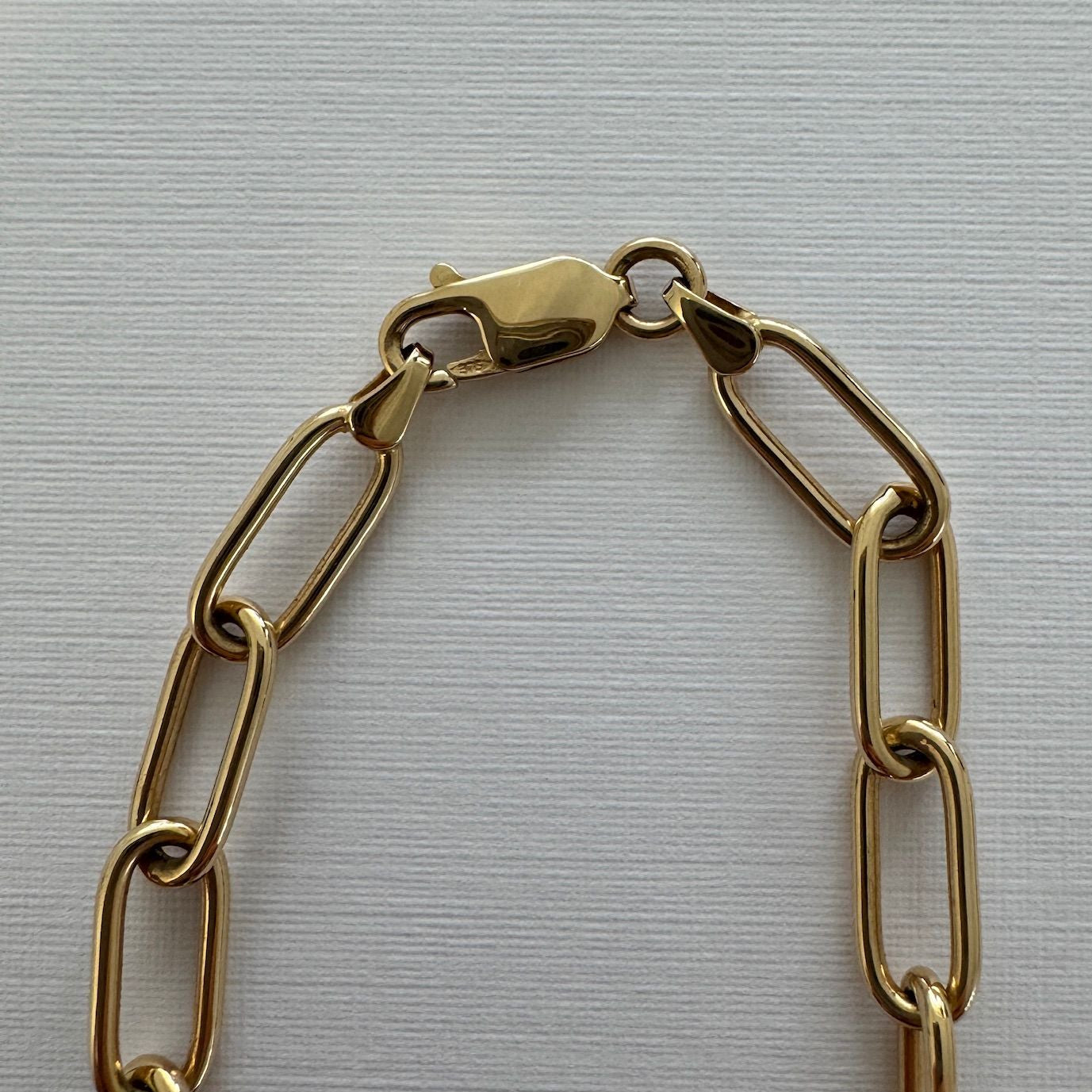 Gold chain bracelet on a light gray background