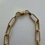 Gold chain bracelet on a light gray background