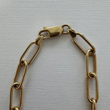 Gold chain bracelet on a light gray background