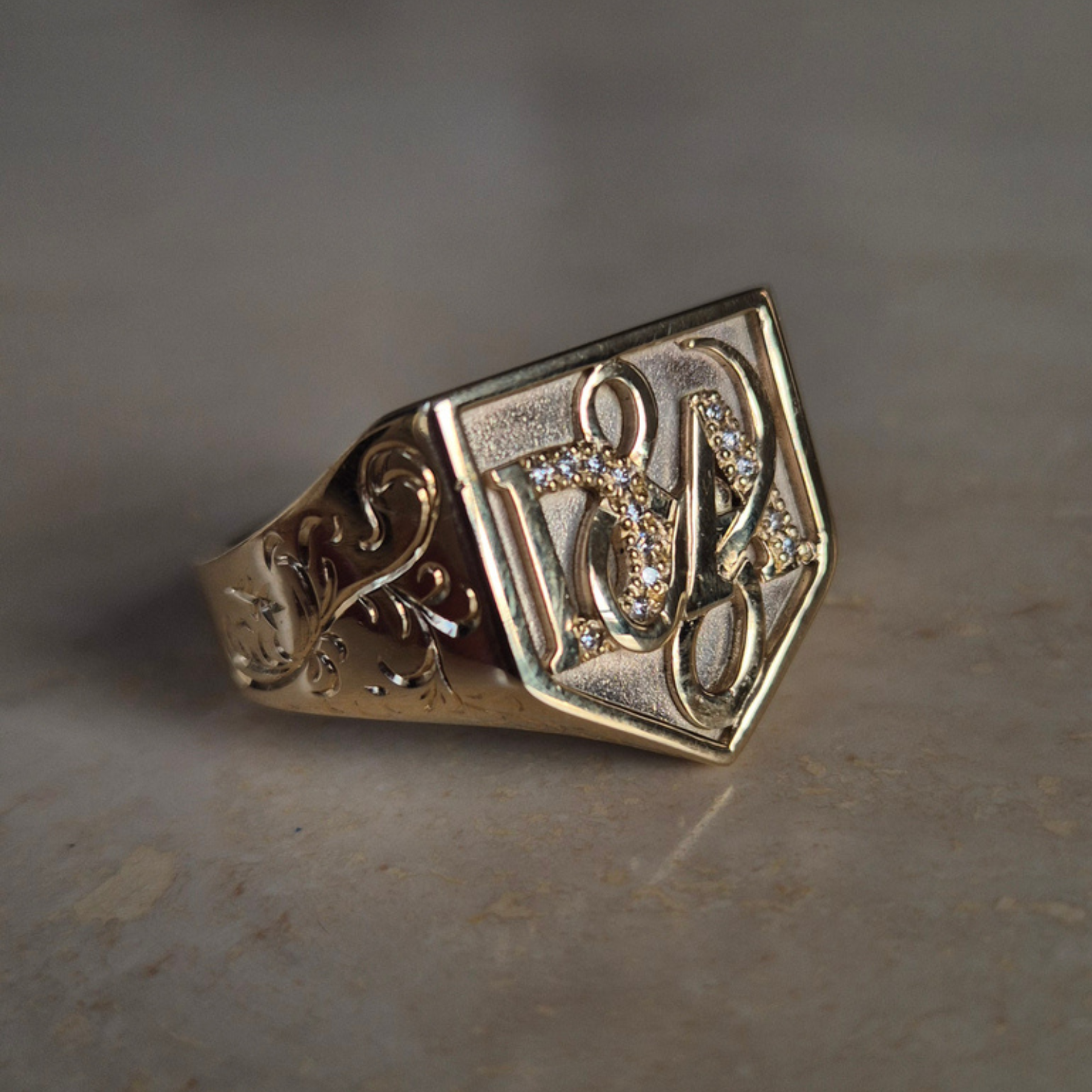 Gold signet with intricate design on a textured surface