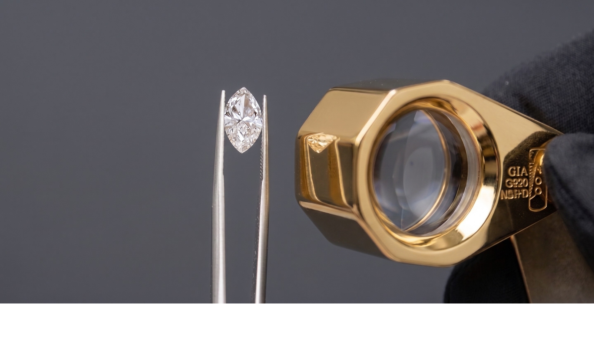 Diamond held by tweezers with a gold loupe against a dark background