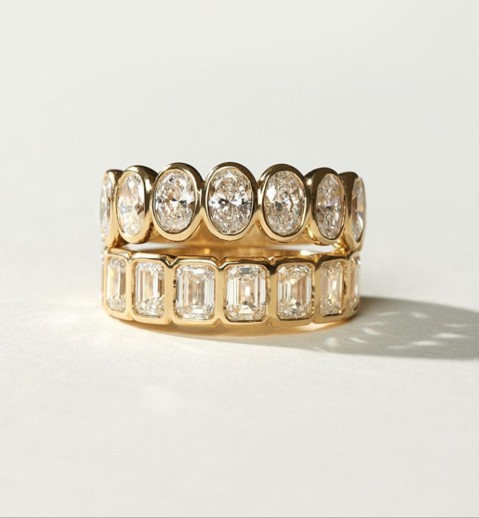 Gold ring with oval-shaped diamonds on a light gray background