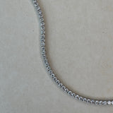 Close-up of a diamond tennis necklace on a light gray background