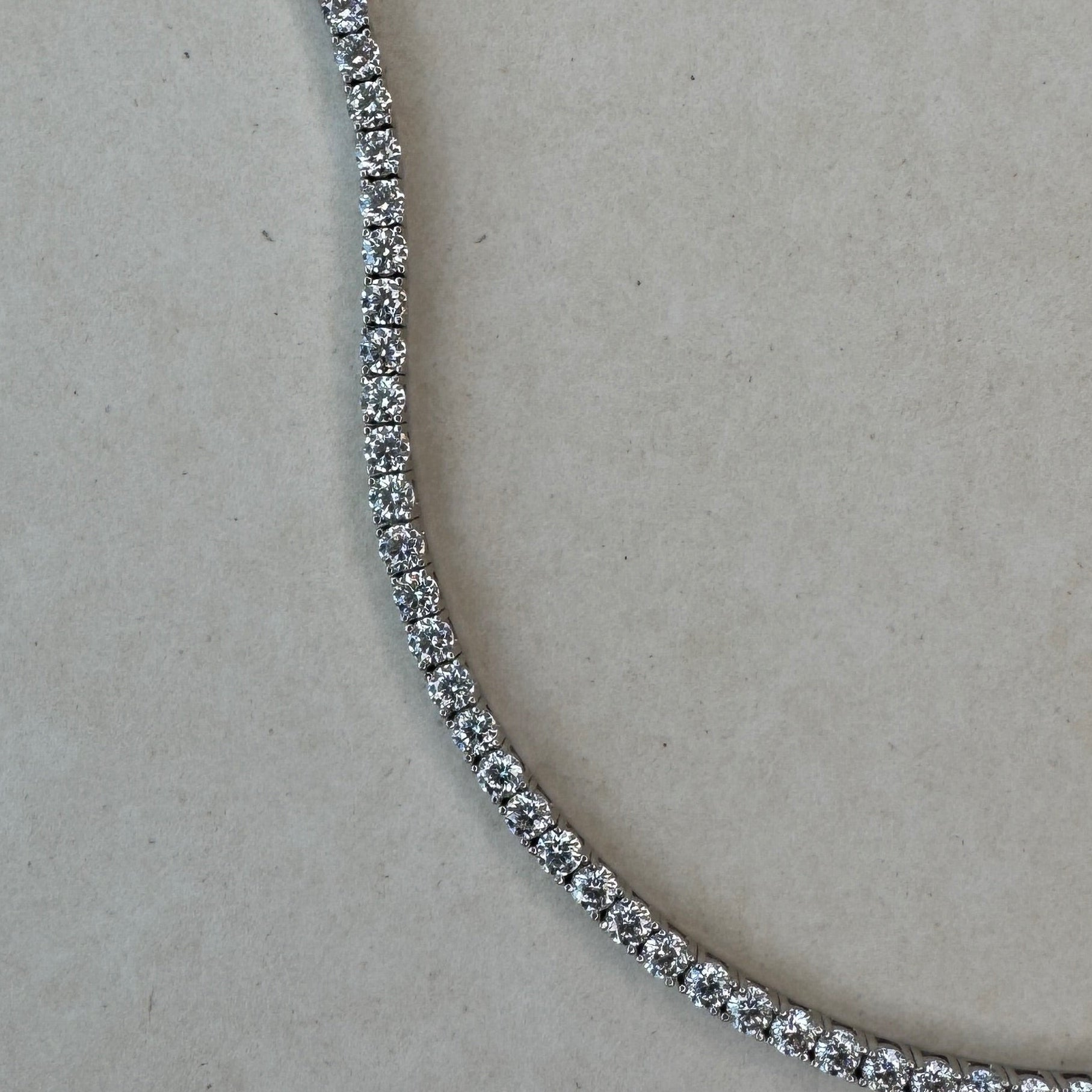 Close-up of a diamond tennis necklace on a light gray background