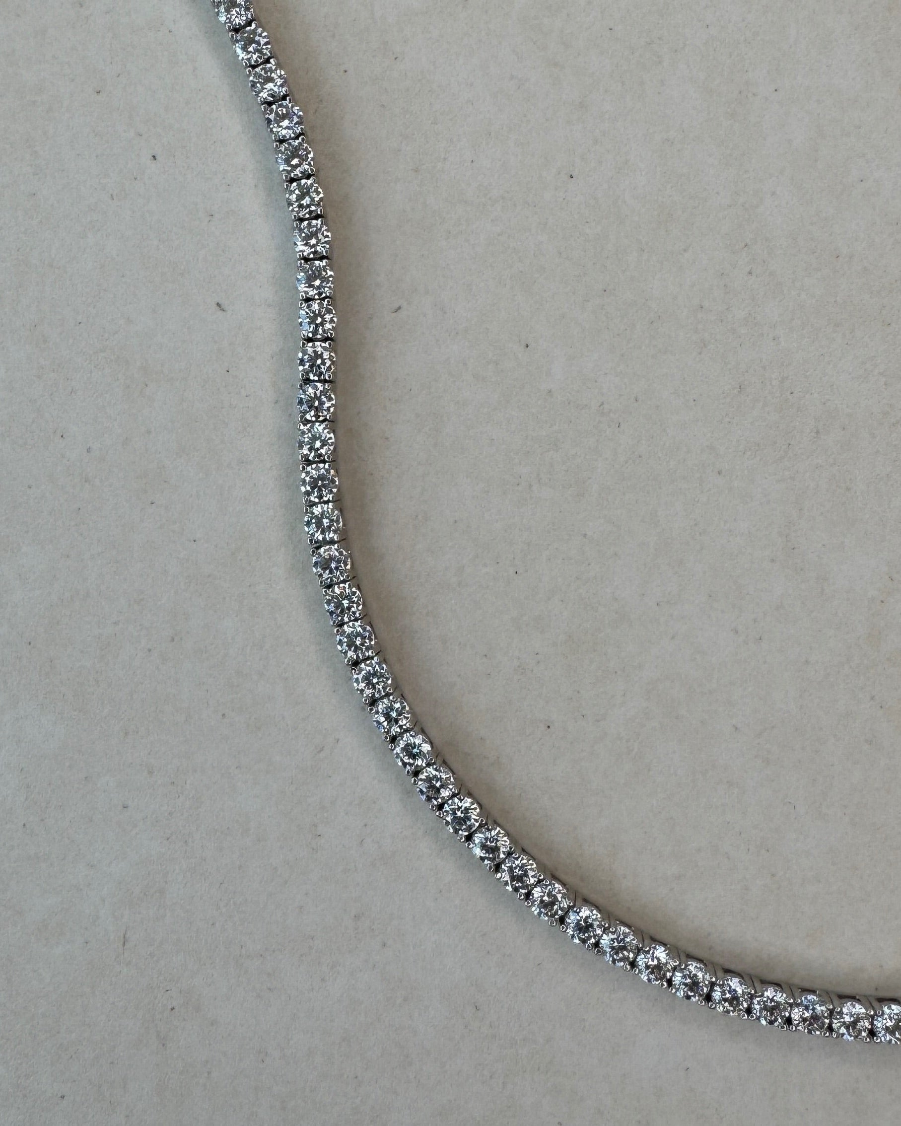Close-up of a diamond tennis necklace on a light gray background