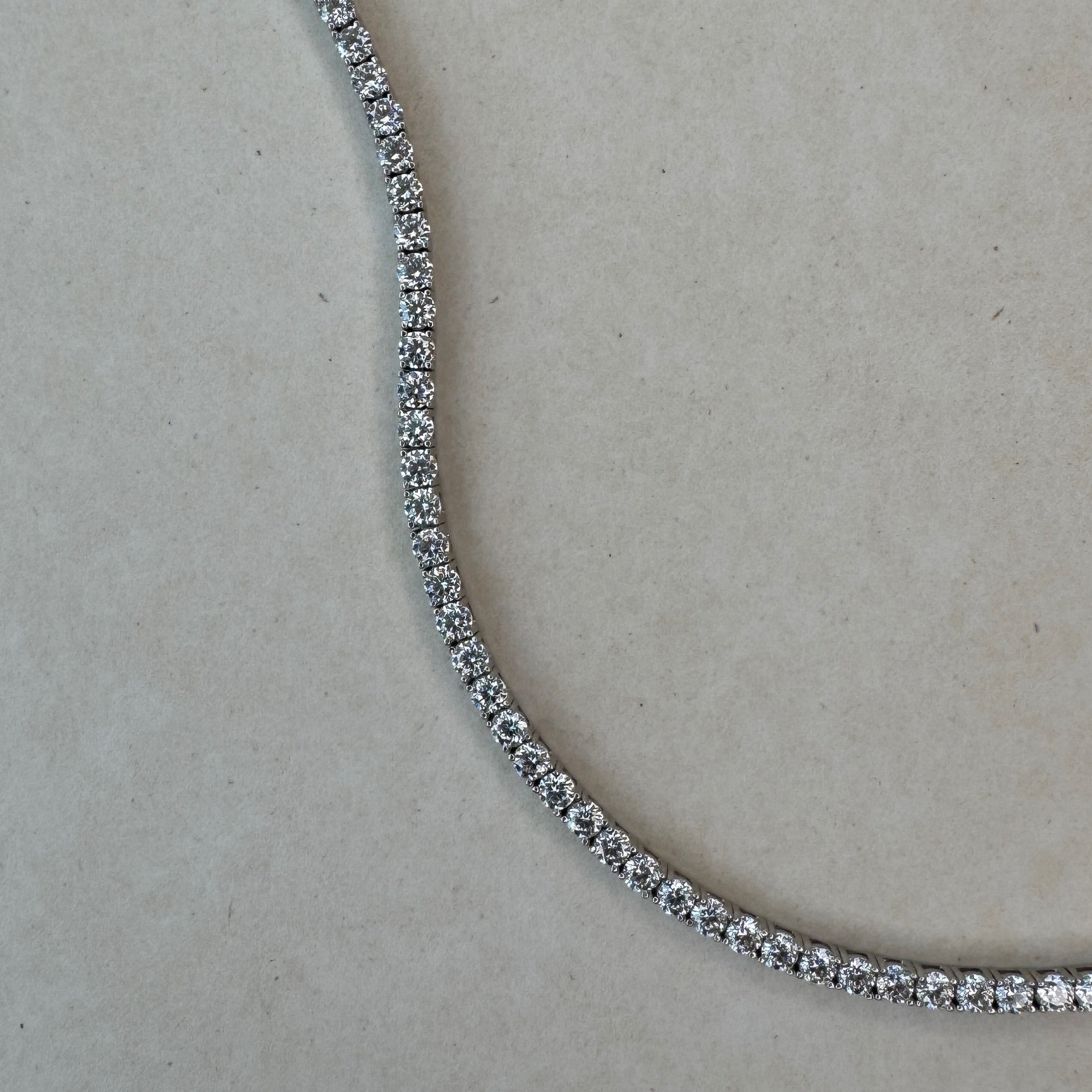 Close-up of a diamond tennis necklace on a light gray background