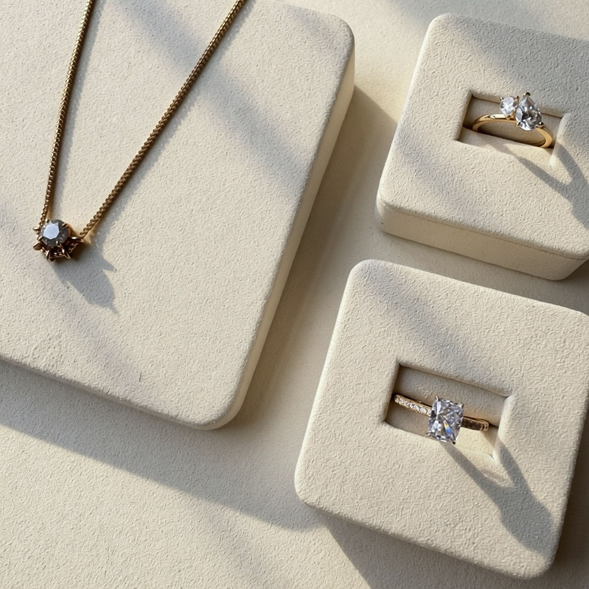 Jewelry set including a necklace and two rings displayed on beige jewelry boxes.