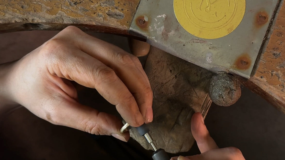 Close-up of hands working on a tool with a yellow circular component on a wooden surface.