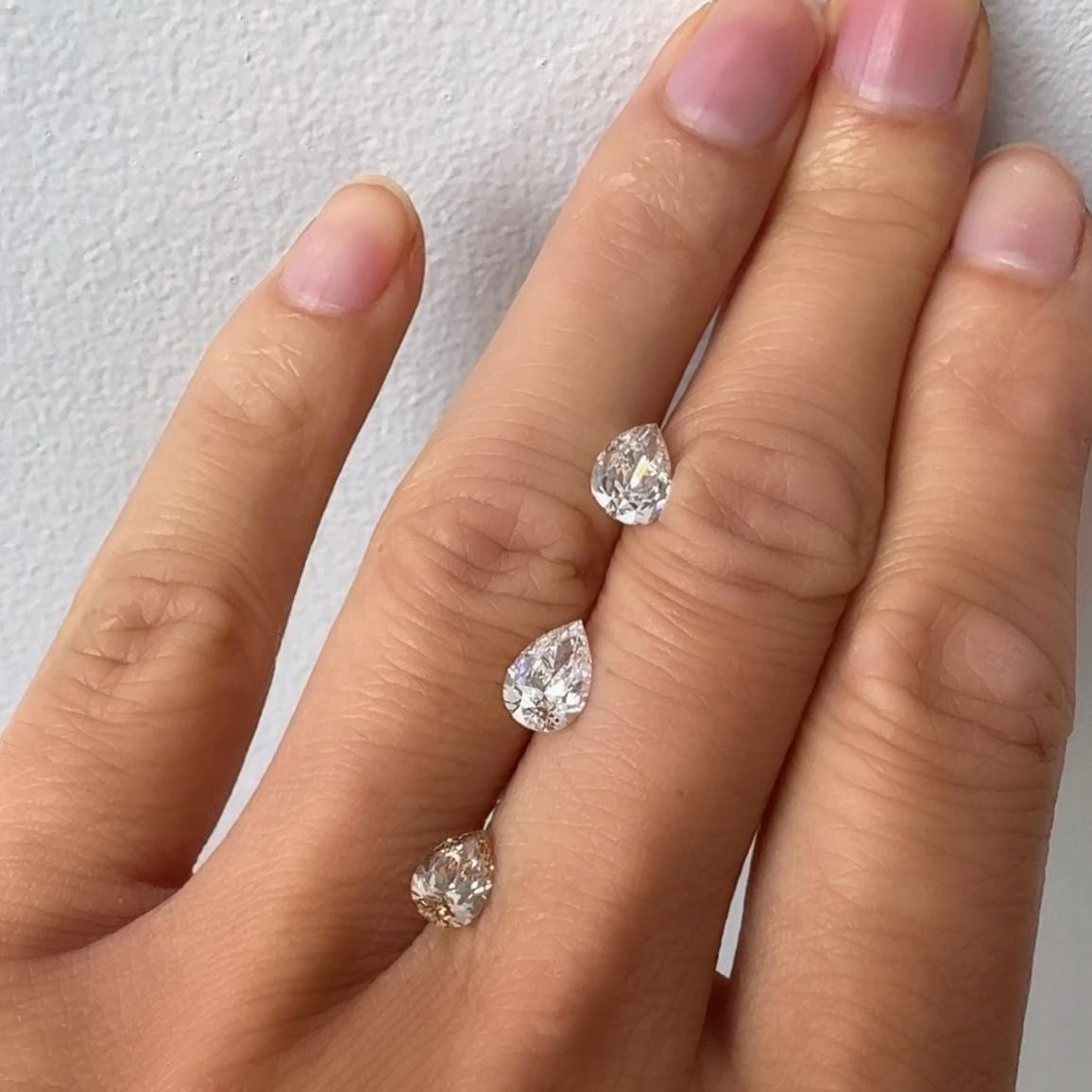 Hand wearing three diamond rings on a plain background