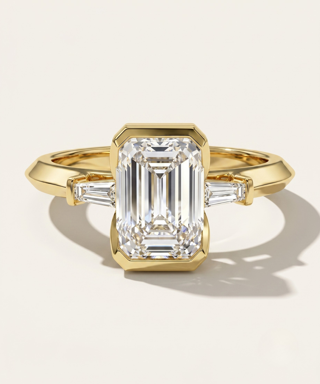 MOHSTEN Montreux 18ct yellow gold three-stone engagement ring with half-bezel emerald cut diamond.
