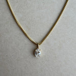 Gold necklace with a diamond pendant on a beige background