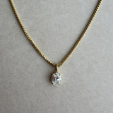 Gold necklace with a diamond pendant on a beige background