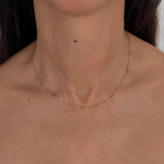 MOHSTEN personalised 9ct gold charm necklace with custom initials and blue birthstones, modeled on the neck.
