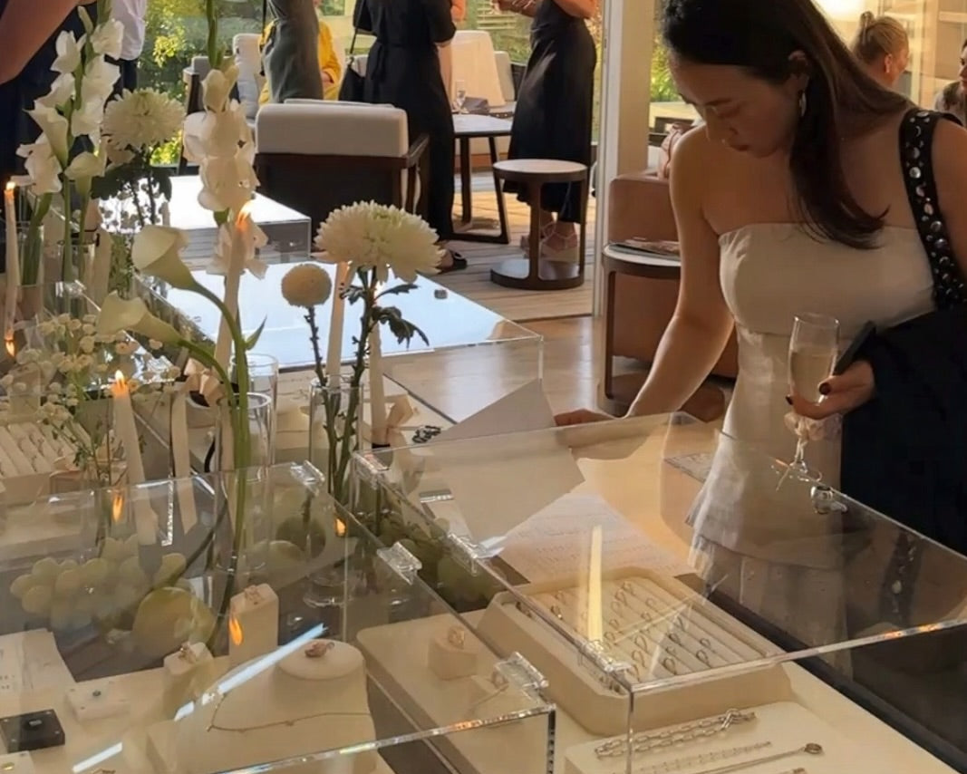 Jewelry display case with rings on a table, people in the background