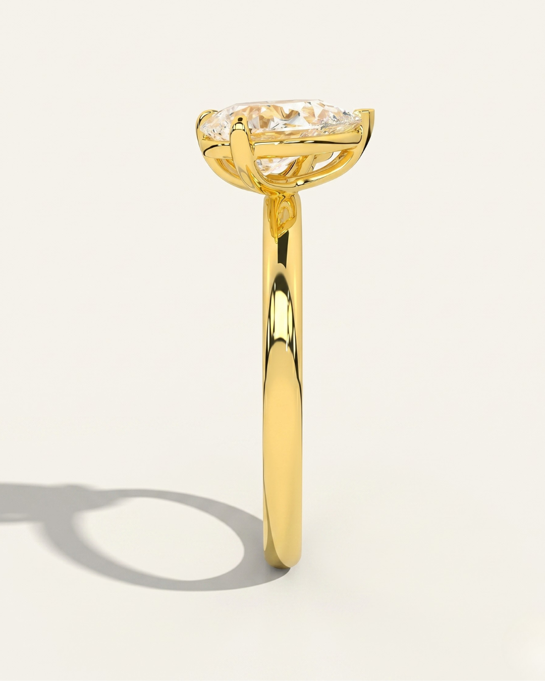 Side profile view of the MOHSTEN Cairo pear diamond Toi et Moi engagement ring in 18ct yellow gold, showcasing the low-profile setting architecture and elegant shadow on a minimalist studio background.