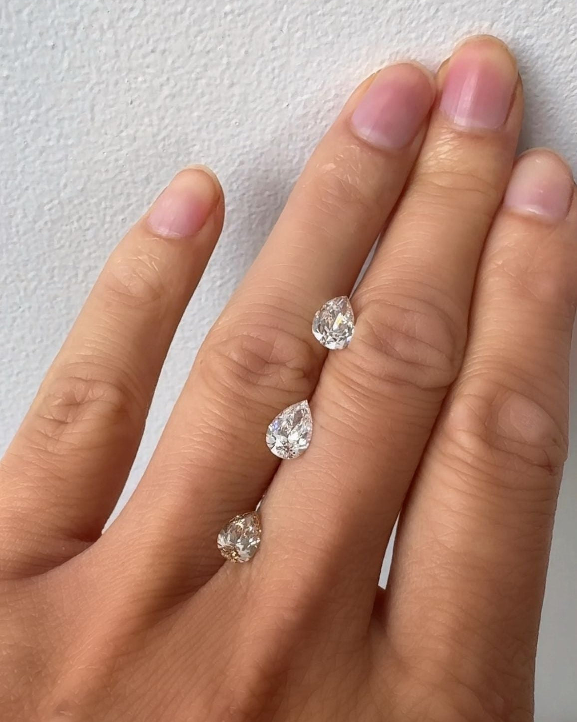 Hand wearing three diamond rings on a plain background