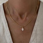 Necklace with a pendant worn by a person against a neutral background