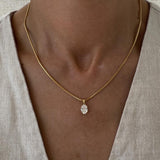 Necklace with a pendant worn by a person against a neutral background