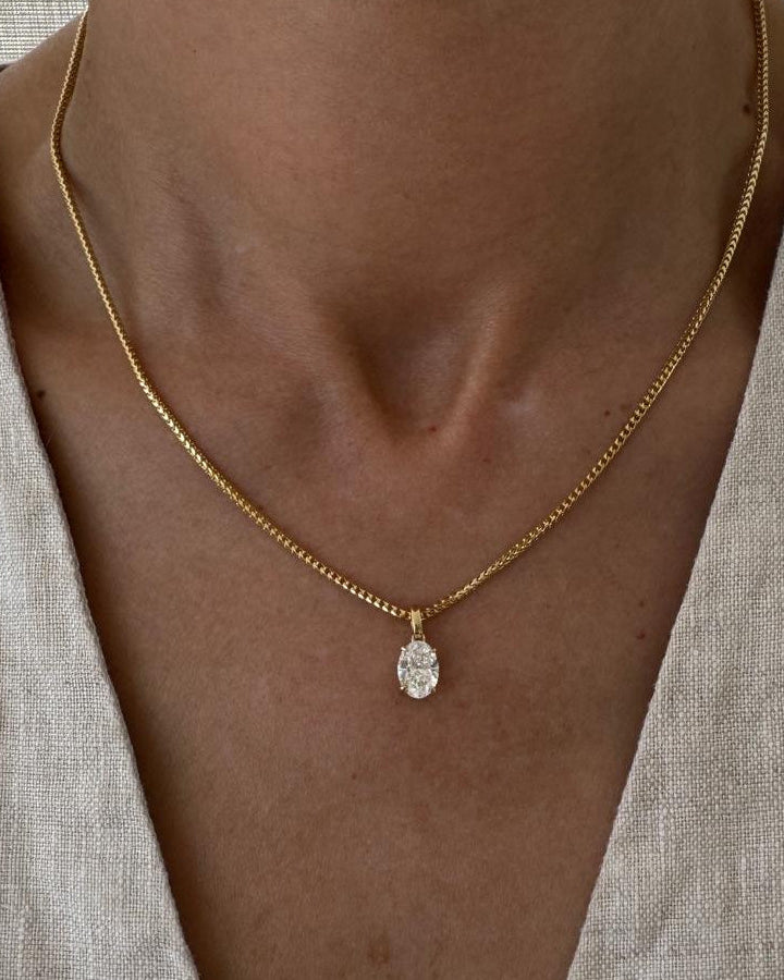 Necklace with a pendant worn by a person against a neutral background