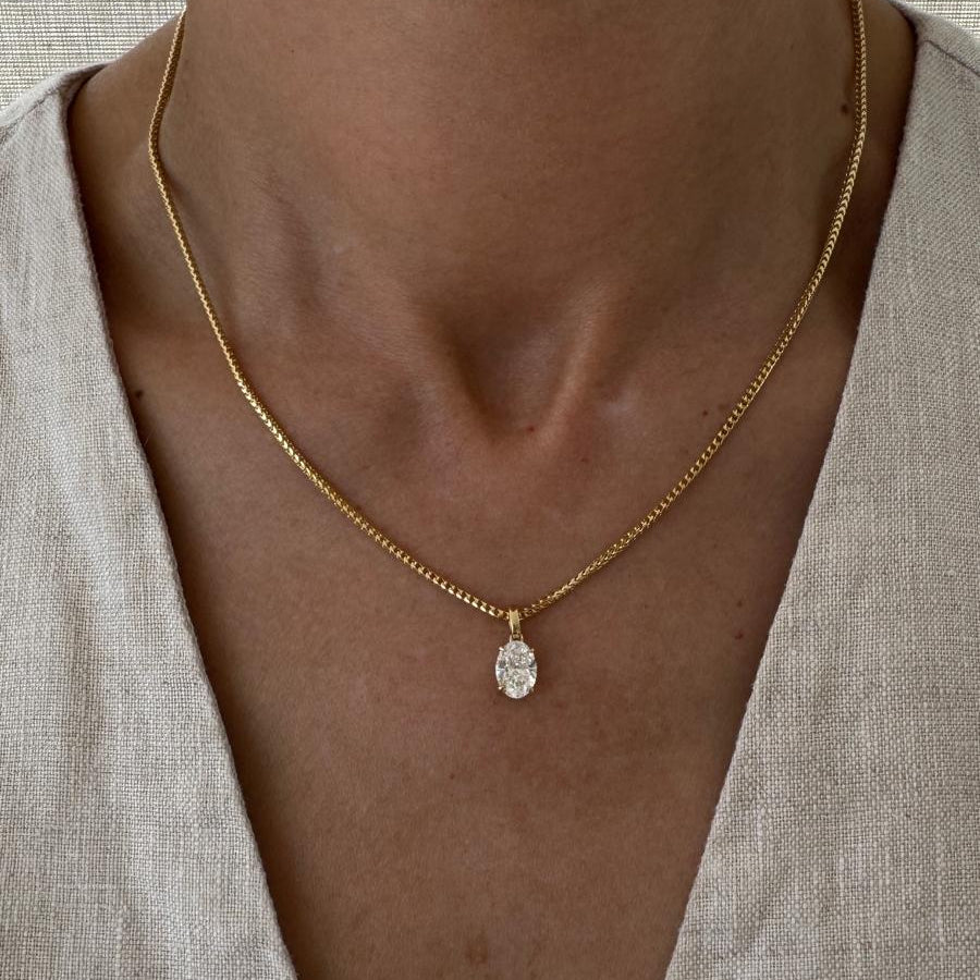 Necklace with a pendant worn by a person against a neutral background