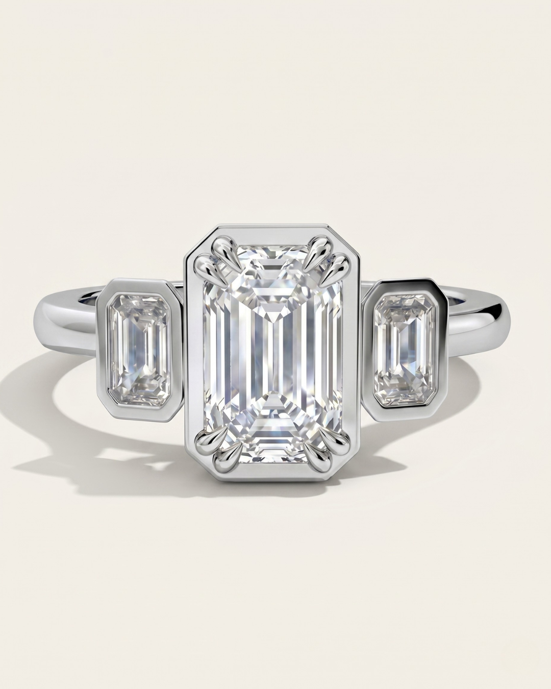 MOHSTEN Duval three-stone emerald cut diamond trilogy engagement ring in polished platinum showcasing an octagonal faux bezel setting.