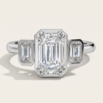 MOHSTEN Duval three-stone emerald cut diamond trilogy engagement ring in polished platinum showcasing an octagonal faux bezel setting.