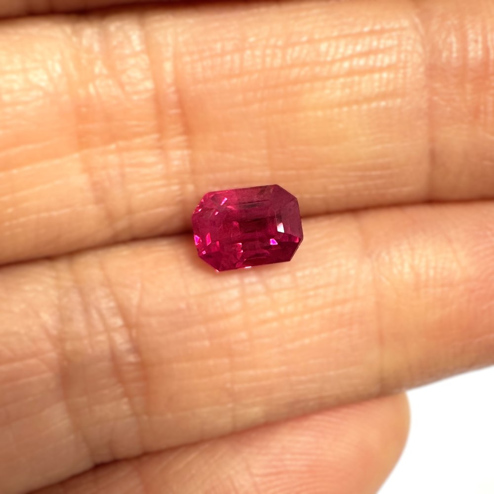 emerald cut ruby between fingers