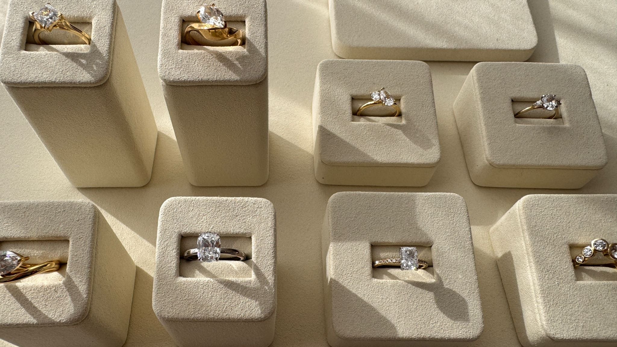 Multiple diamond rings in small beige boxes on a matching surface