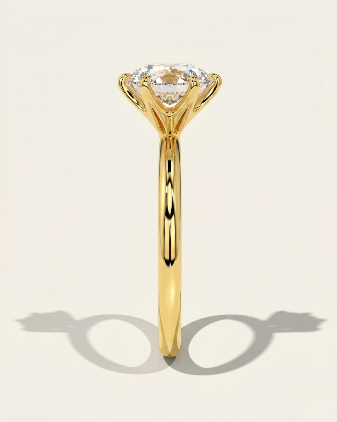 MOHSTEN Jaipur round diamond solitaire engagement ring in 18ct yellow gold from a direct side profile view, highlighting the architectural 6-prong setting and the elegant shadow cast on a warm studio background.