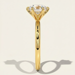 MOHSTEN Jaipur round diamond solitaire engagement ring in 18ct yellow gold from a direct side profile view, highlighting the architectural 6-prong setting and the elegant shadow cast on a warm studio background.