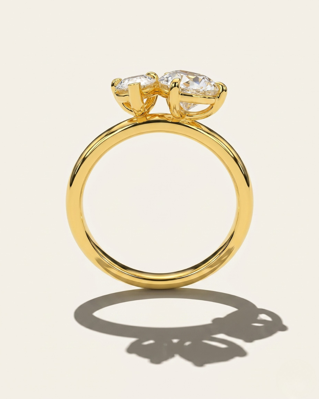 MOHSTEN Cairo pear diamond Toi et Moi engagement ring in 18ct yellow gold from a standing side-profile view, highlighting the circular band and low-profile prong setting architecture casting a sharp architectural shadow.