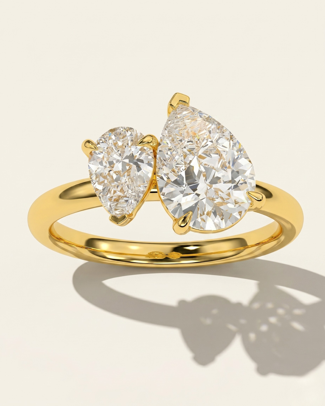 MOHSTEN Cairo pear diamond Toi et Moi engagement ring in 18ct yellow gold, showcasing a crisp macro top view of the two asymmetrical pear-cut diamonds and their distinct architectural shadow on a warm studio background.