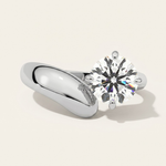 MOHSTEN Granada asymmetric round diamond solitaire engagement ring in polished platinum showcasing a face-on studio view of the offset round brilliant centre diamond on a bold, sculptural wide-swept band casting a soft shadow.