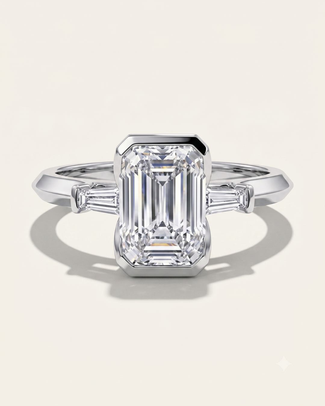 MOHSTEN Montreux 18ct white gold three-stone engagement ring with emerald cut diamond and tapered baguettes.