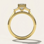 MOHSTEN Montreux 18ct yellow gold three-stone engagement ring standing front view with emerald cut diamond.