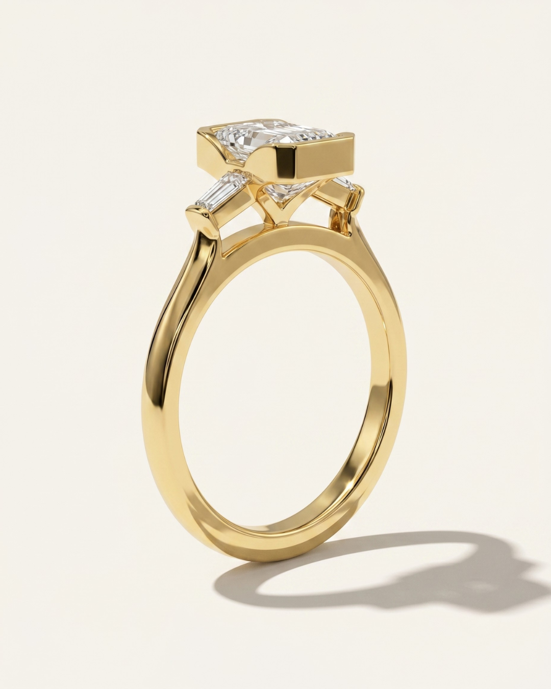 MOHSTEN Montreux 18ct yellow gold three-stone engagement ring side profile with emerald cut diamond and knife-edge band.