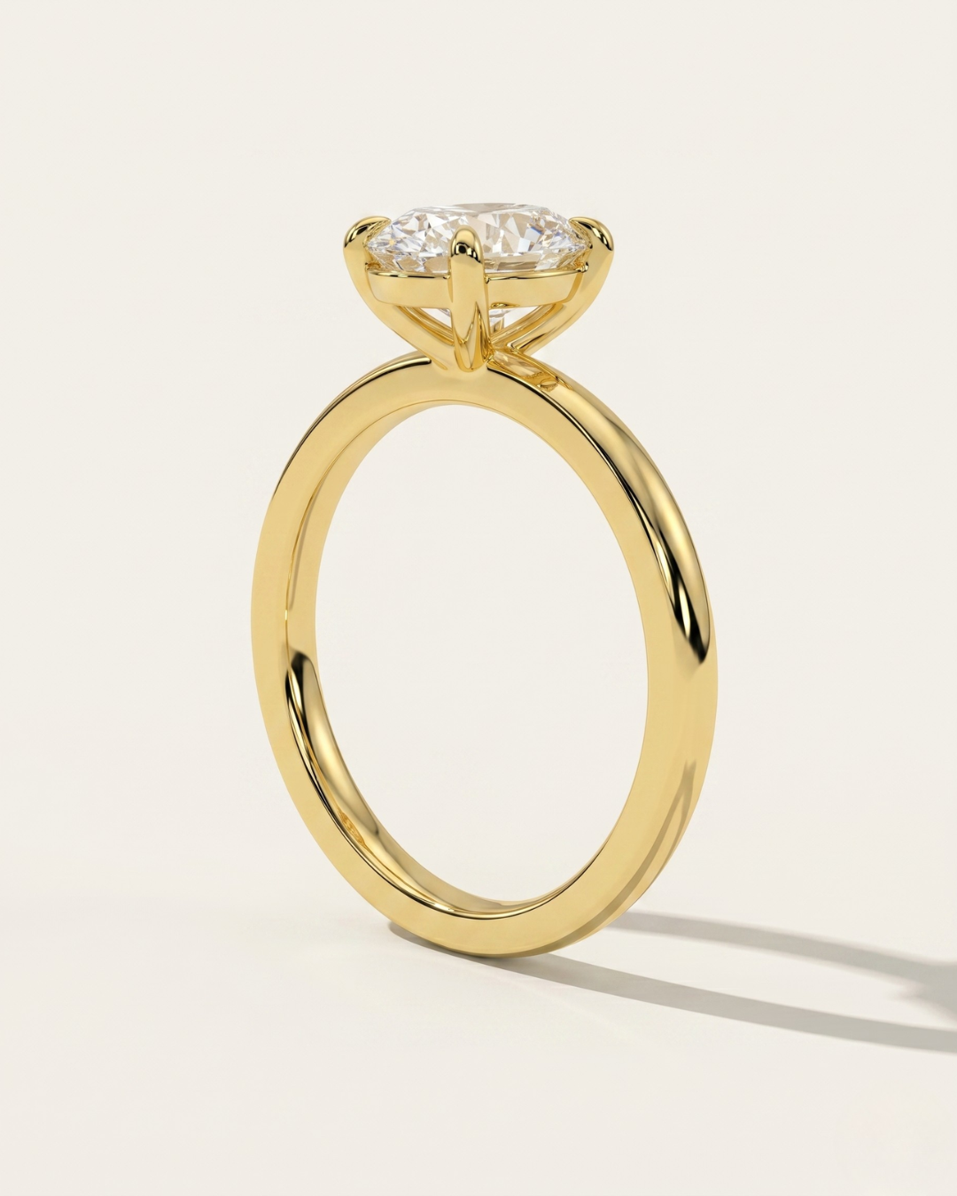 MOHSTEN Osaka oval diamond solitaire engagement ring in 18ct yellow gold from a direct side profile standing view, highlighting the architectural 4-prong basket setting and its elegant shadow on a minimalist studio background.